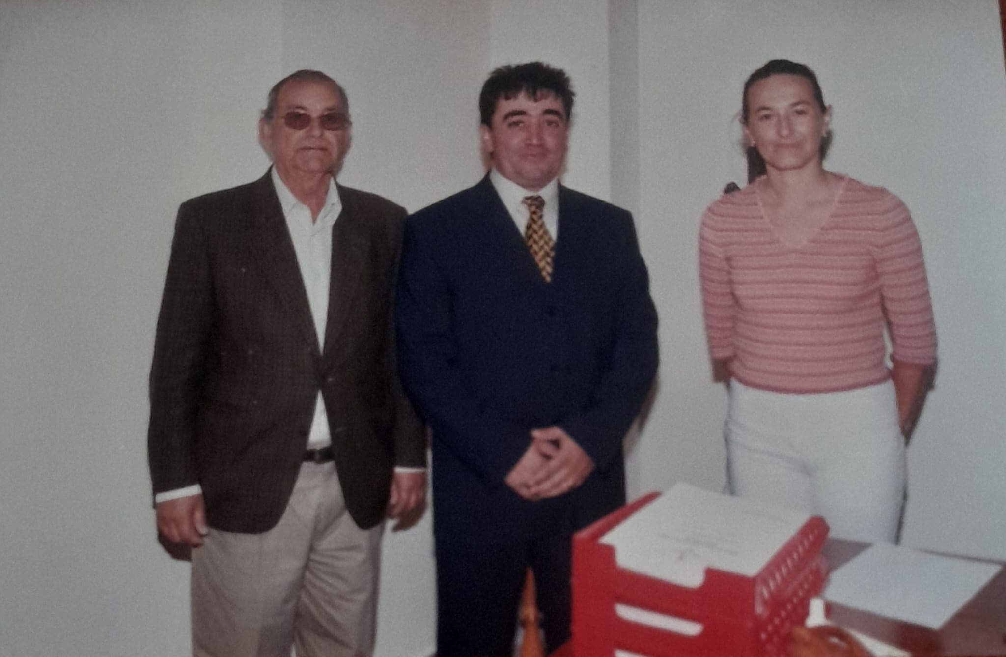 Fernando González Cruz, de traje, acompañado de otras dos personas junto a unas cajas apiladas